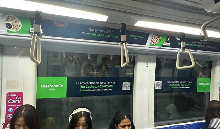 TM7 overhead cards and window stickers live in an MRT carriage